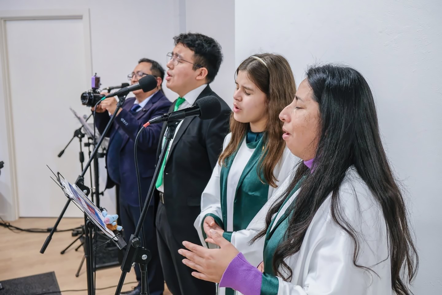 Un grupo canta con los ojos cerrados frente a los micrófonos, durante un culto en la iglesia