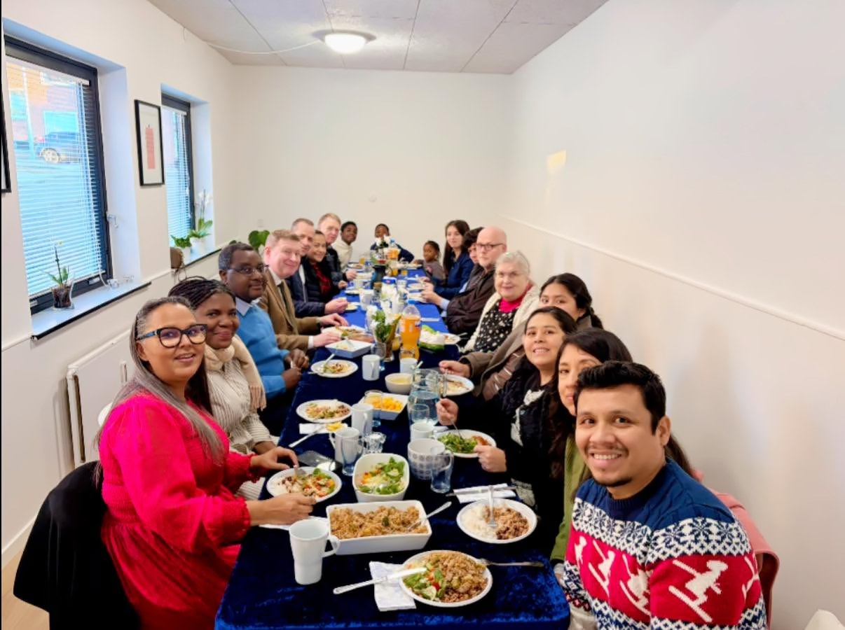 Miembros de la iglesia comiendo juntos en una mesa larga